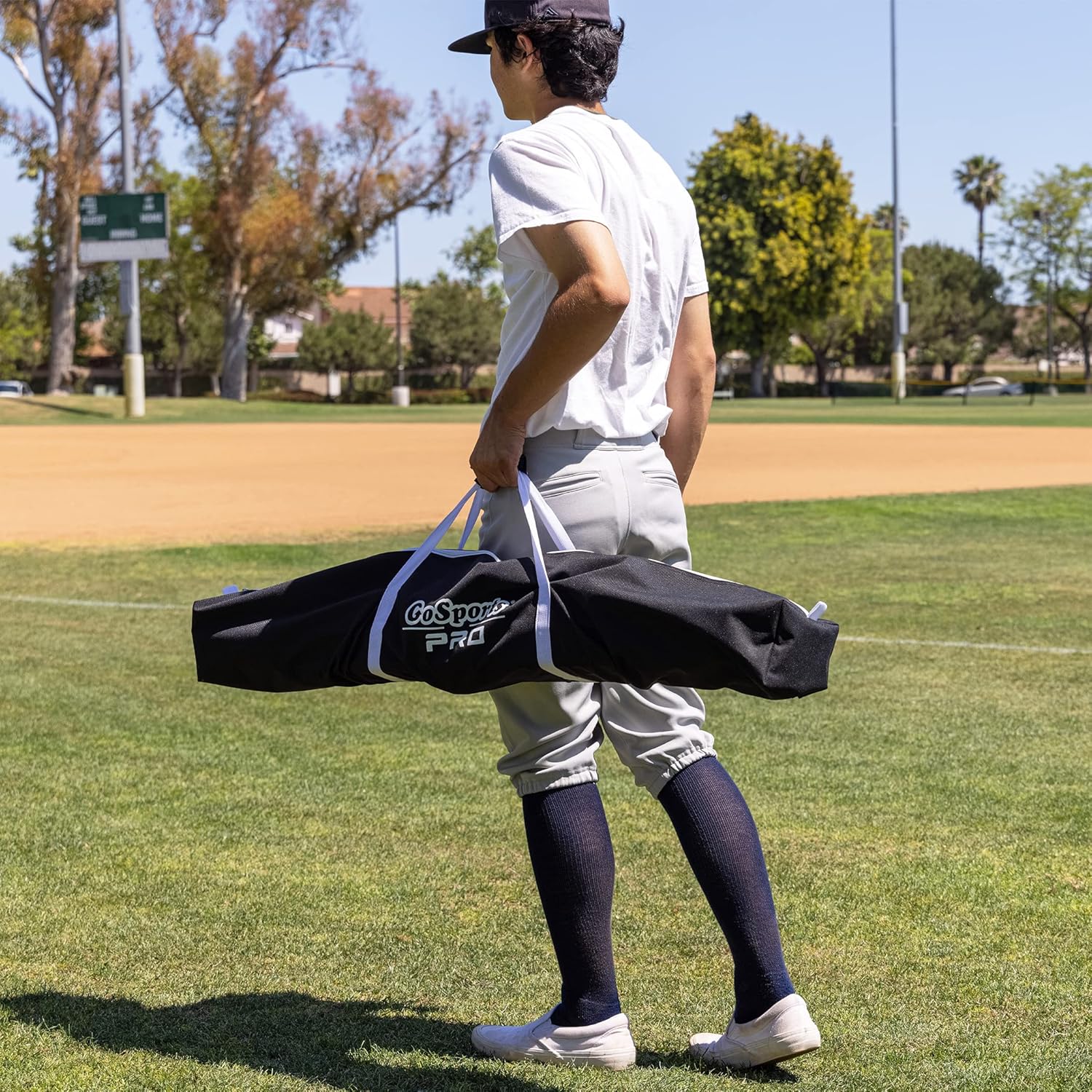 Batter carrying GoSports 7 ft x 7 ft Baseball & Softball Practice Hitting & Pitching Net in its case