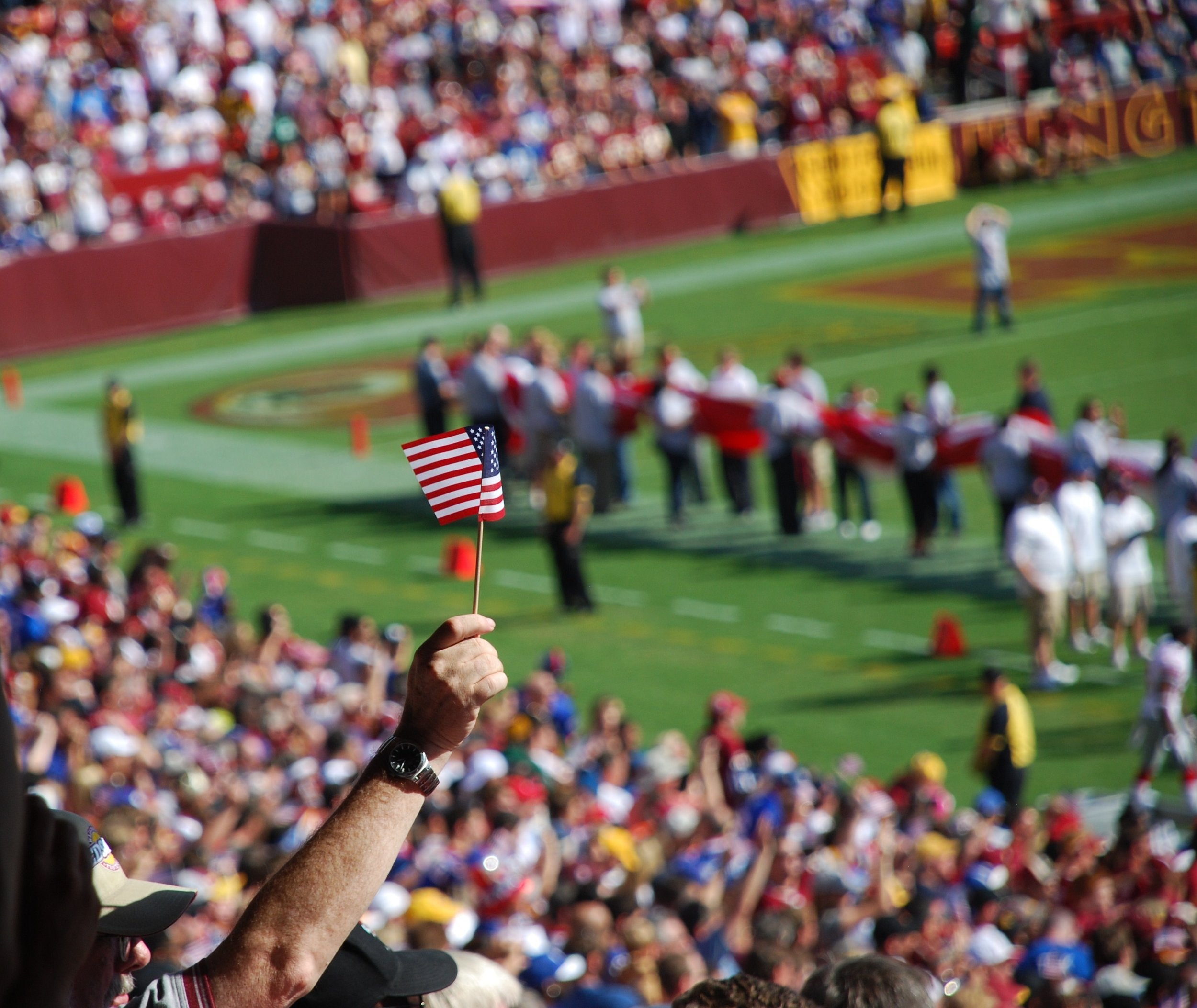 Man holds up US flag at football stadium